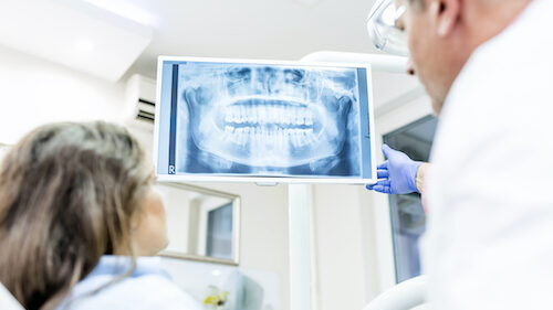 A dentist shows a dental patient an x-ray of their teeth