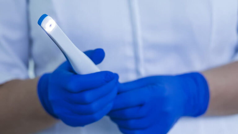 man with blue gloves holding intraoral camera