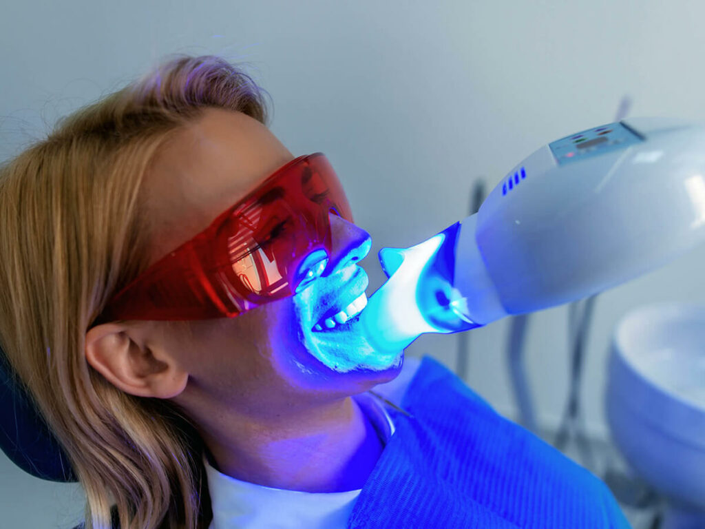 woman getting teeth whitened in dental chair